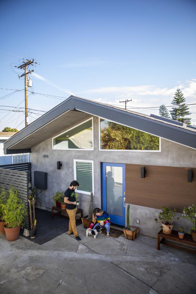 Two people and a dog outside a modern accessory dwelling unit.