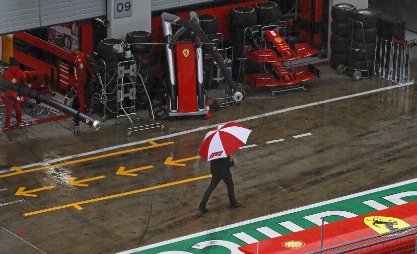 A man with an umbrella walks in the rain in the pit lane prior the delayed third practice session for the Styrian Formula One Grand Prix at the Red Bull Ring racetrack in Spielberg, Austria, Saturday, July 11, 2020. The Styrian F1 Grand Prix will be held on Sunday. (Leonhard Foeger/Pool via AP)