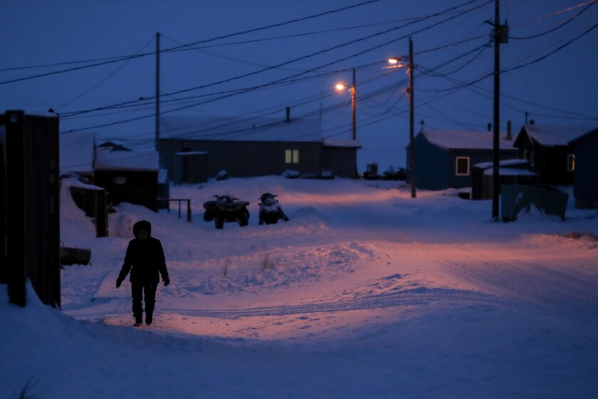 FILE - In this Jan. 20, 2020, file photo, a woman walks before dawn in Toksook Bay, Alaska, a mostly Yuip'ik village on the edge of the Bering Sea. The U.S. Supreme Court will hear oral arguments Monday, April 19, 2021, in a case that will determine who is eligible to receive more than $530 million in federal virus relief funding set aside for tribes more than a year ago. More than a dozen Native American tribes sued the U.S. Treasury Department to keep the money out of the hands of Alaska Native corporations, which provide services to Alaska Natives but do not have a government-to-government relationship with the United States. (AP Photo/Gregory Bull, File)
