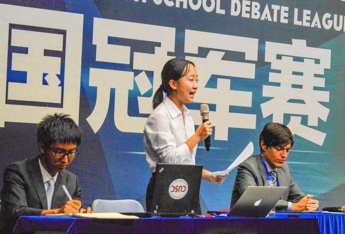 Cloris Zhang, 15, makes a point during the National High School Debate League of China championship. She is flanked by teammate Sherman Wang, 17, left, and league President David Weeks.