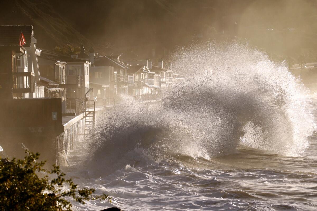 Waves crash into the sea walls of homes.