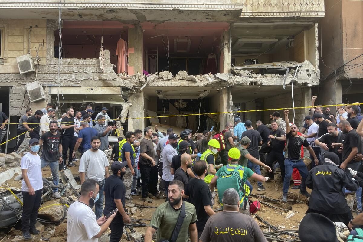 People gather near a damaged building at the scene of an Israeli missile strike in a southern suburb of Beirut.