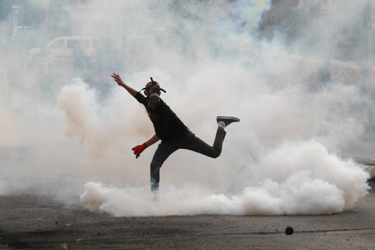 A Palestinian protester throws a tear gas canister back during clashes with Israeli security forces at the main entrance of the West Bank city of Bethlehem.