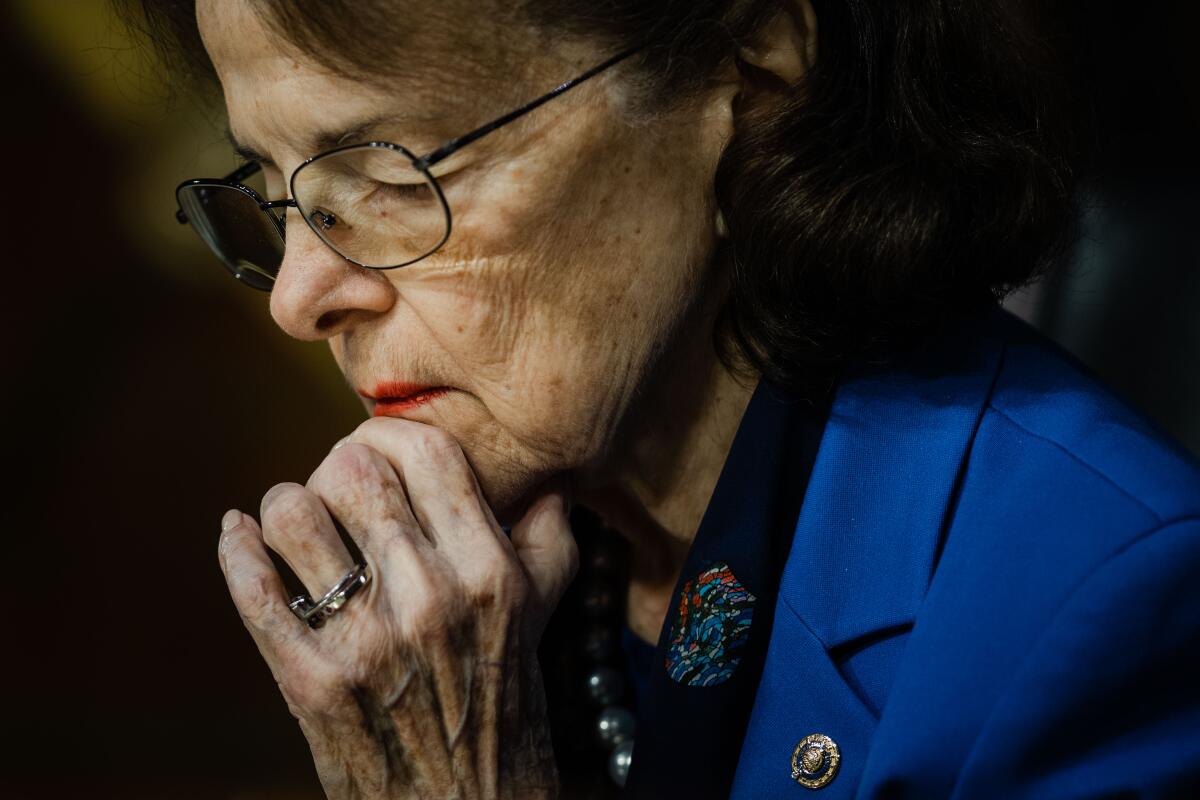 A closeup of Dianne Feinstein with her eyes closed, her left hand on her chin