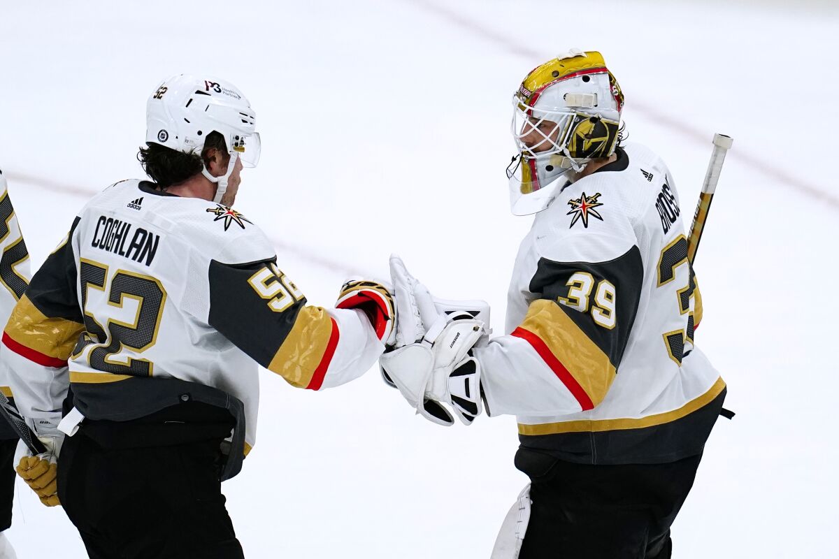 Vegas Golden Knights goalie Laurent Brossoit (39) celebrates with defenseman Dylan Coghlan (52) as time expires in the team's NHL hockey game against the Arizona Coyotes on Friday, Dec. 3, 2021, in Glendale, Ariz. The Golden Knights won 7-1. (AP Photo/Ross D. Franklin)