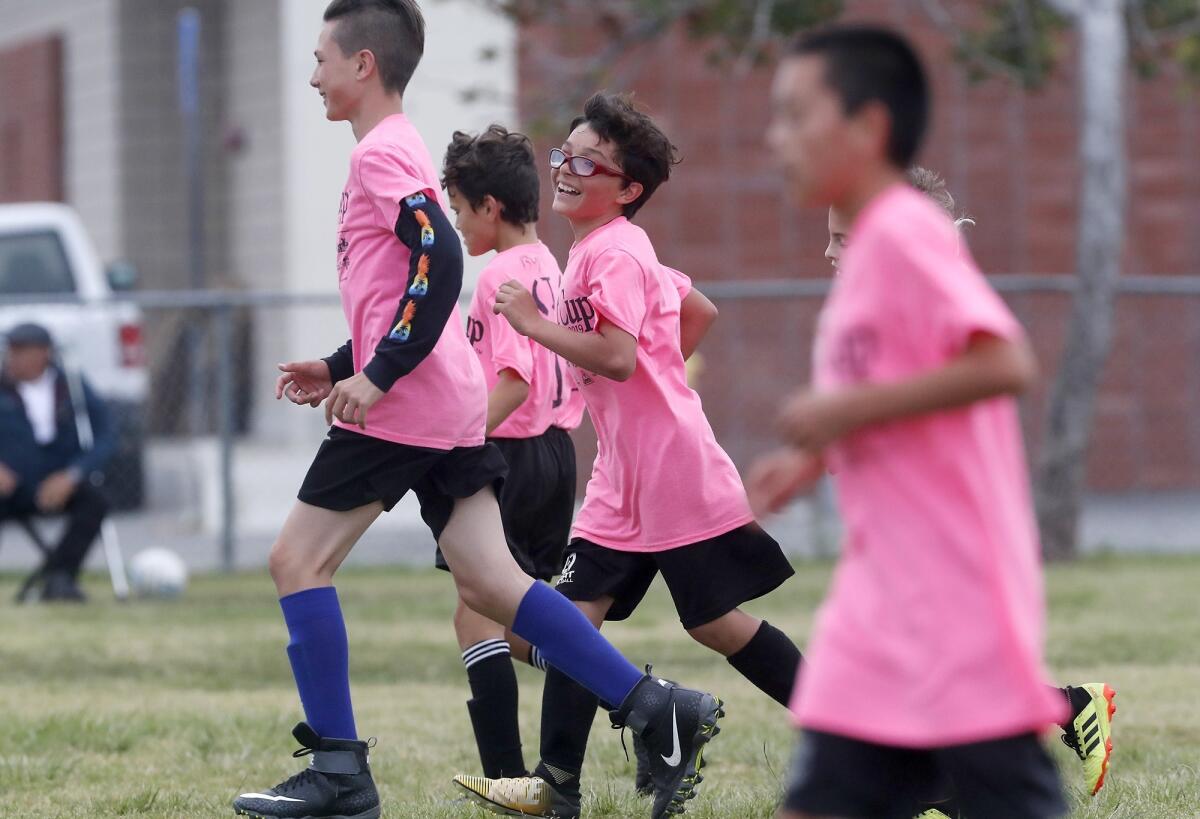 Newport Elementary's Trevor Glynn, center, smiles after scoring a goal against Carden Hall in a boys’ fifth- and sixth-grade Bronze Division pool-play match at the Daily Pilot Cup on Friday at Costa Mesa High.