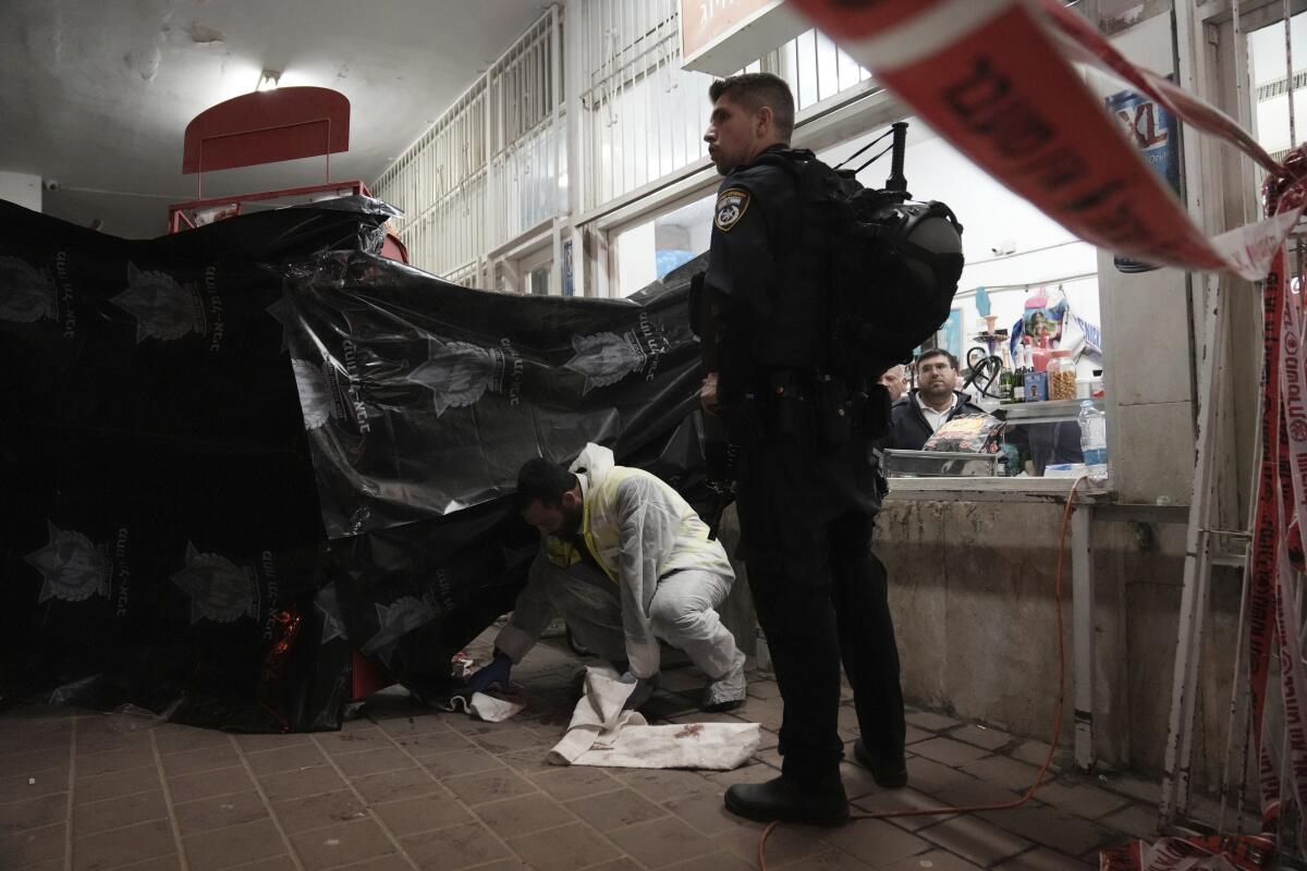 A man in protective gear cleans a walkway after a fatal shooting in Israel
