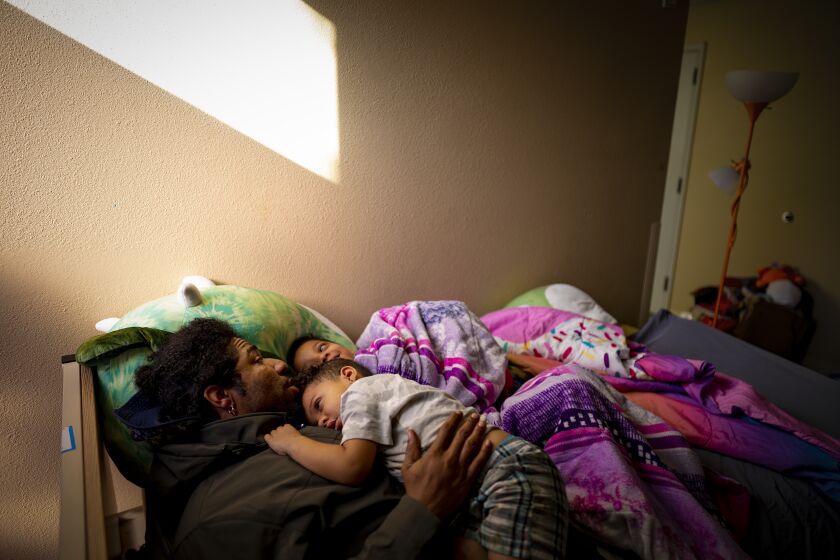San Diego, CA - December 23: At San Diego Rescue Mission on Friday, Dec. 23, 2022 in San Diego, CA., Christopher Johnson, 38 tries to wake two of his four children (Anthony Marquis Johnson, 7, and Noah Johnson, 3) up in the morning. Johnson is a single dad living at the San Diego Rescue Mission. With him are Izahi Marquis Johnson, 9, Anthony Marquis Johnson, 7, Kaliah Marie Johnson, 4, Noah Johnson, 3. (Nelvin C. Cepeda / The San Diego Union-Tribune)