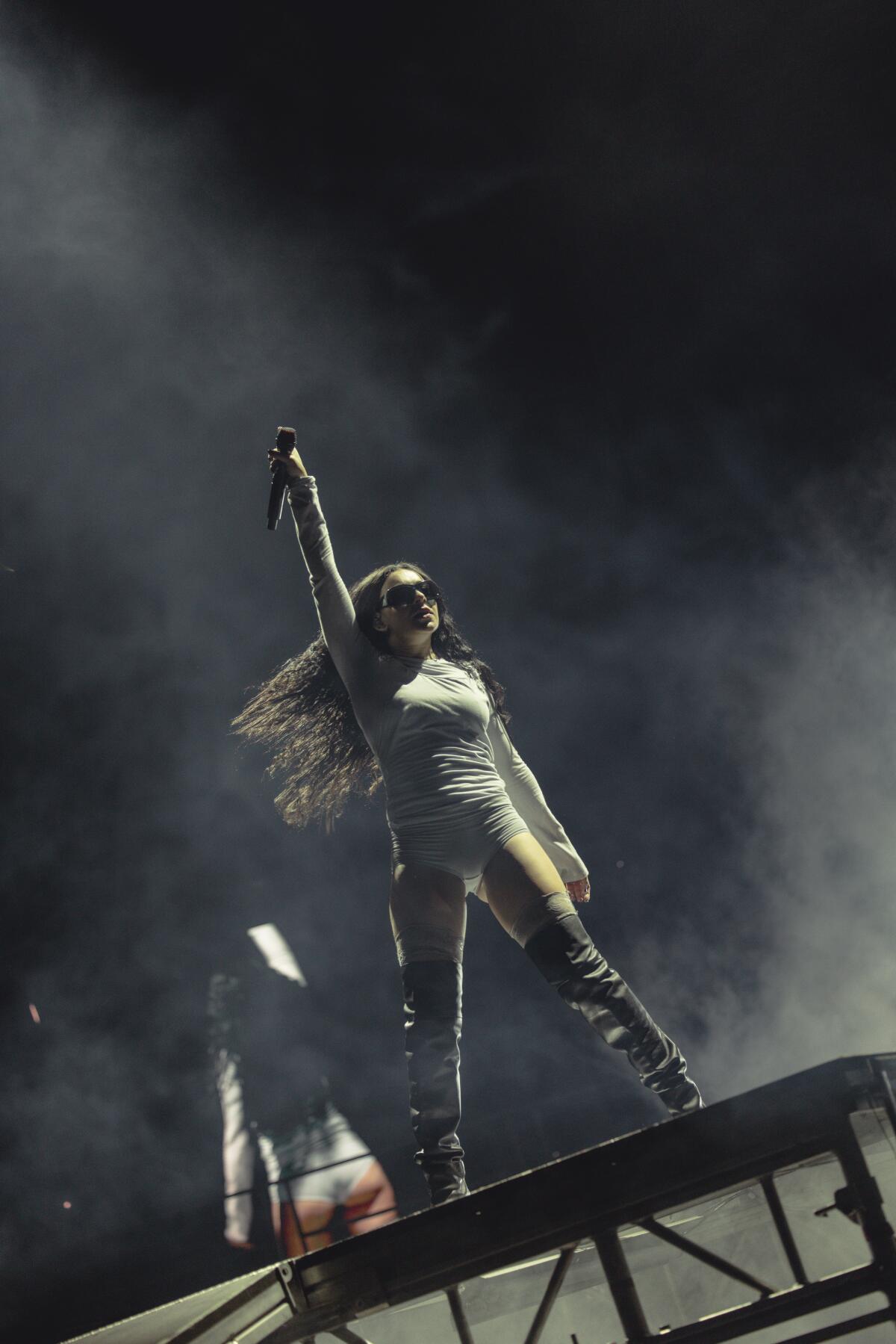 Charli XCX strikes a dramatic pose during a concert.