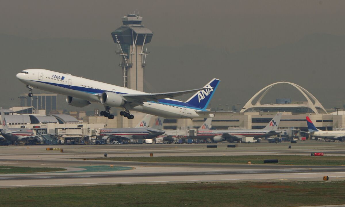 An All Nippon Airways plane, angled upward, above the runway at LAX.