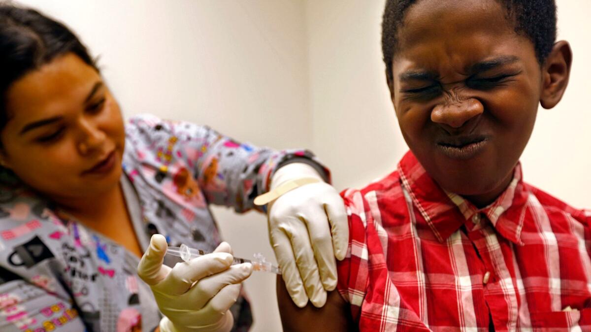 Desmond Sewell, 12, is given his vaccinations by medical assistant Jessica Reyes at the Lou Colen Children's Health and Wellness Center in Mar Vista.