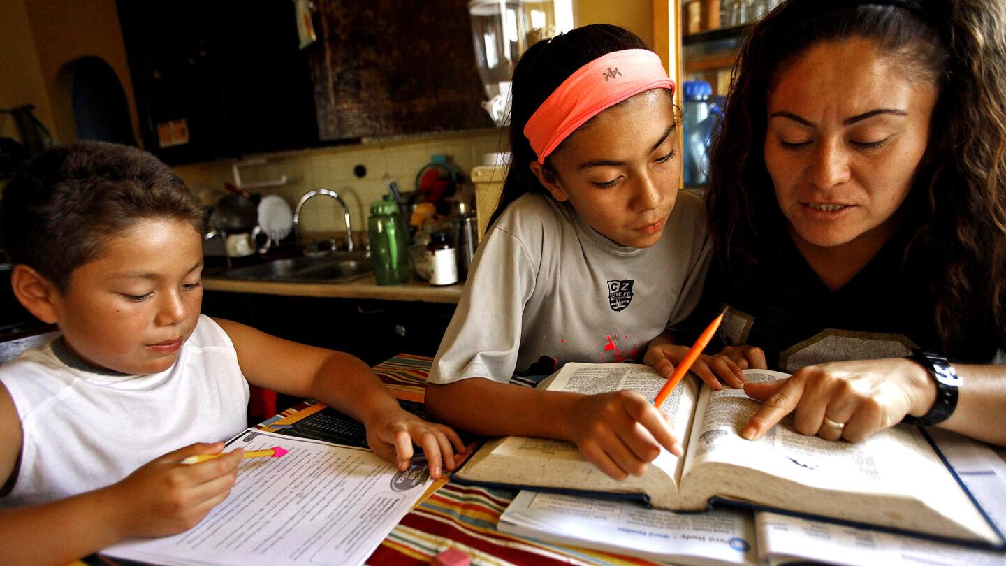 Erika Hilario, right, and her daughter, Luisa, 11, look up the definition of a word as her son, Erick, 8, works on his homework in their Boyle Heights home. Hilario runs her house like an Eastside "tiger mom."