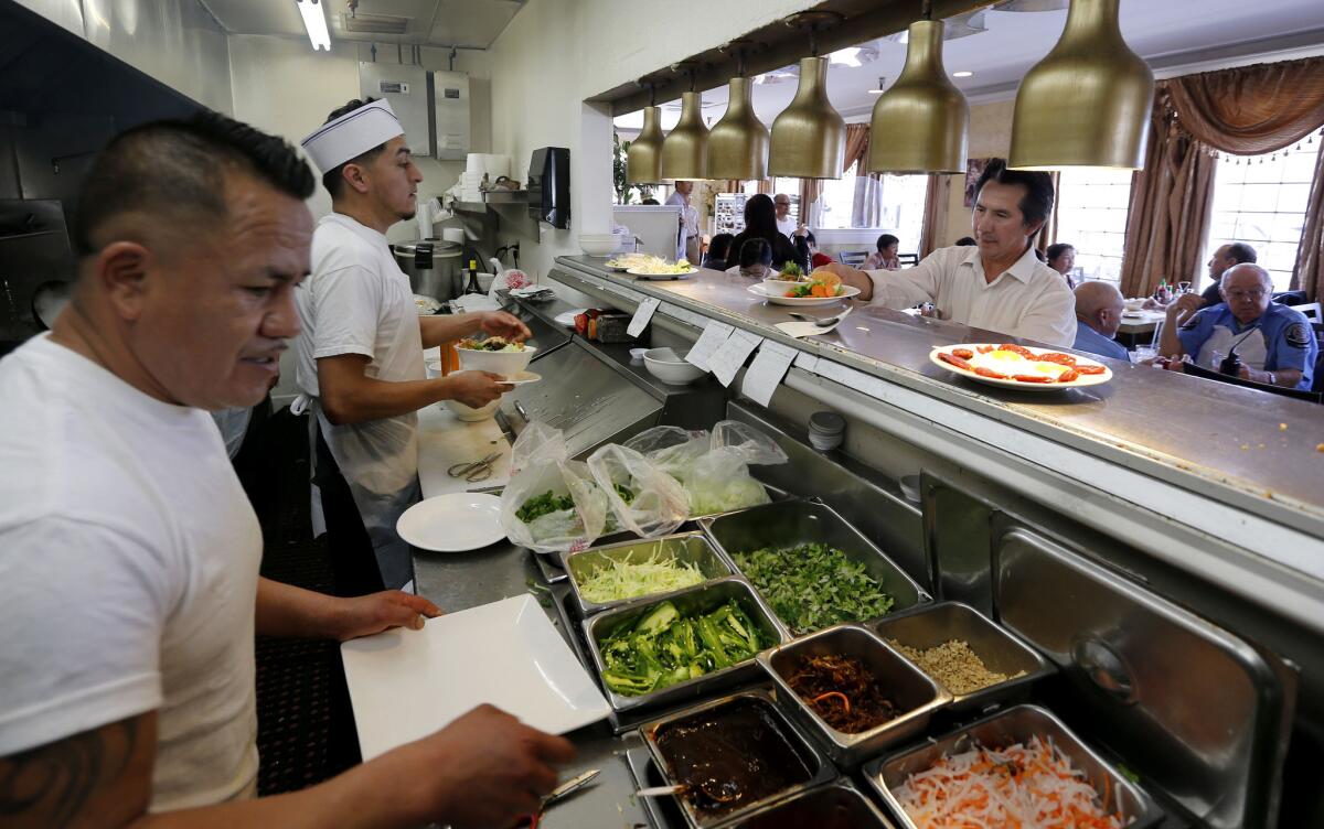 Roberto Torres, right, picks up meals prepared by chef Juan Ramirez, left, and Omar Reynoso, middle.