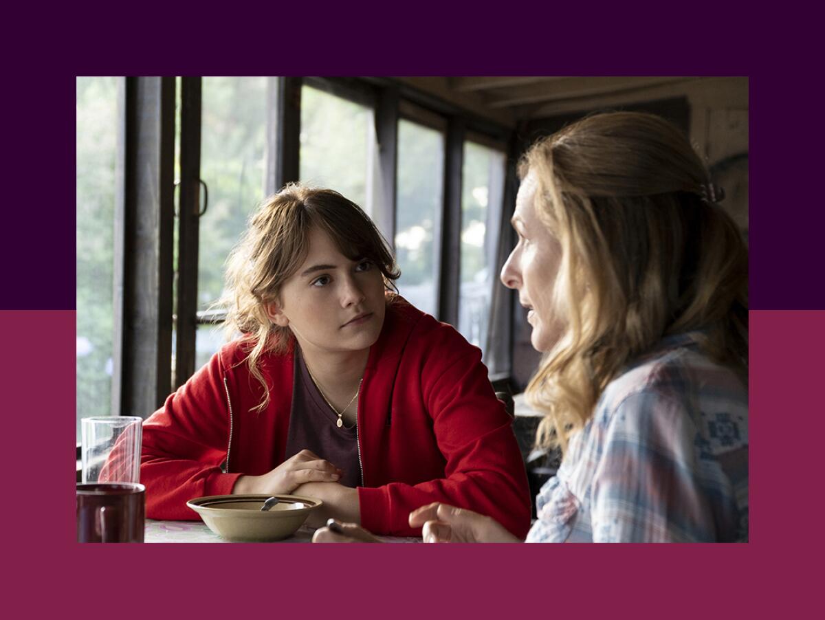 A daughter looks across a table at her mother in a movie scene.