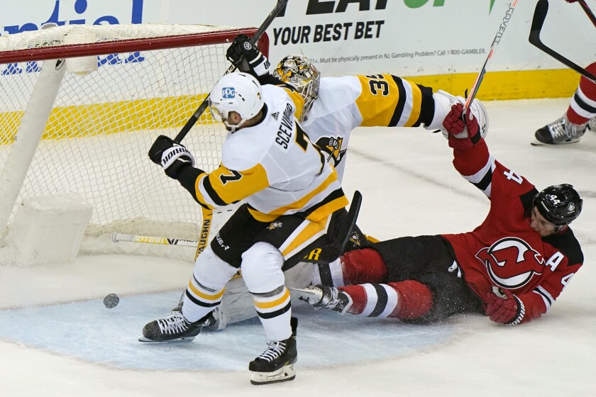 Pittsburgh Penguins center Colton Sceviour (7) and goaltender Tristan Jarry (35) defend against a shot by New Jersey Devils left wing Miles Wood (44) who fell to the ice while scoring a goal during the first period of an NHL hockey game, Sunday, April 11, 2021, in Newark, N.J. (AP Photo/Kathy Willens)