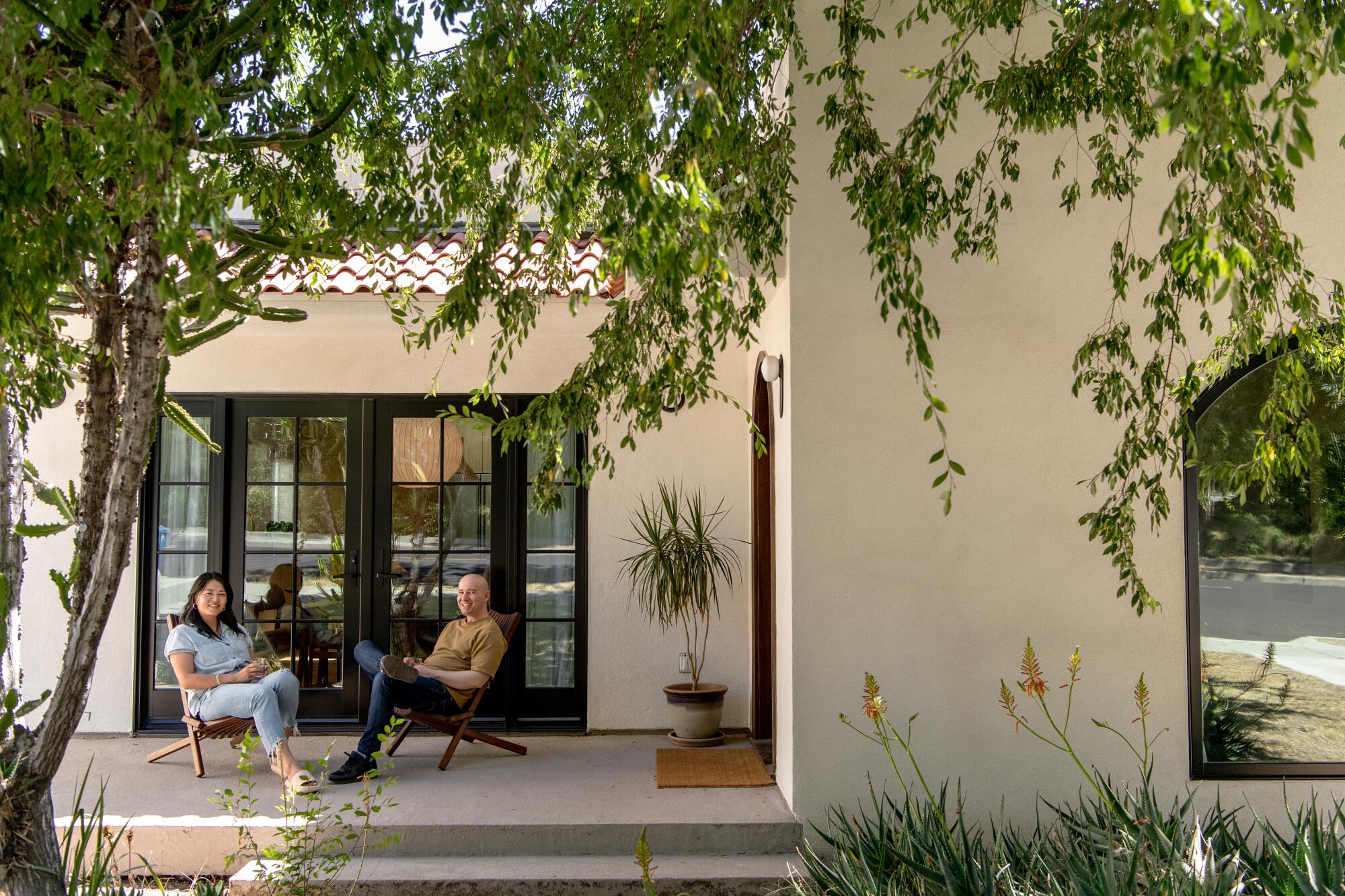 Jing Guo and Gabriel Taylor Russ sit on a patio outside their Spanish bungalow