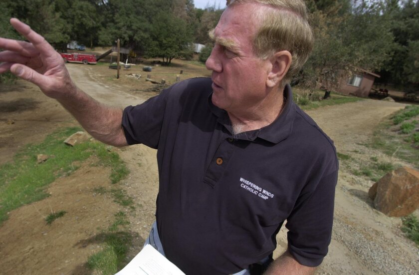 In a 2004 photo, Don Kojis, co-founder of Whispering Winds Catholic Camp in Julian, talks about fire damage in the area.