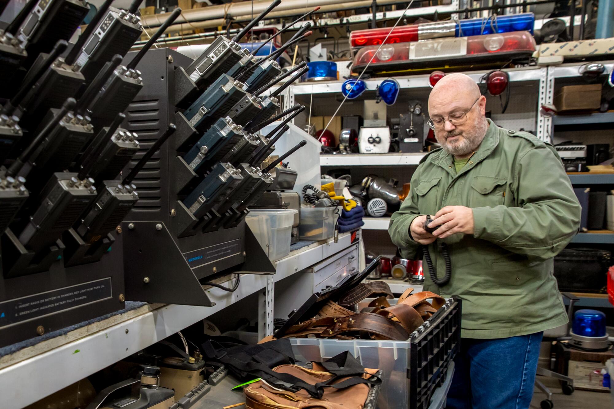 John Tibbetts sorts through police gear at History for Hire prop warehouse.