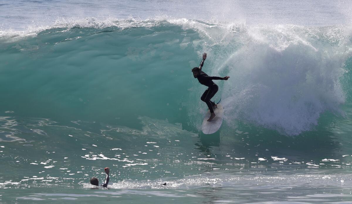 A surfer shoots down the face of a glassy green wave in Newport Beach.