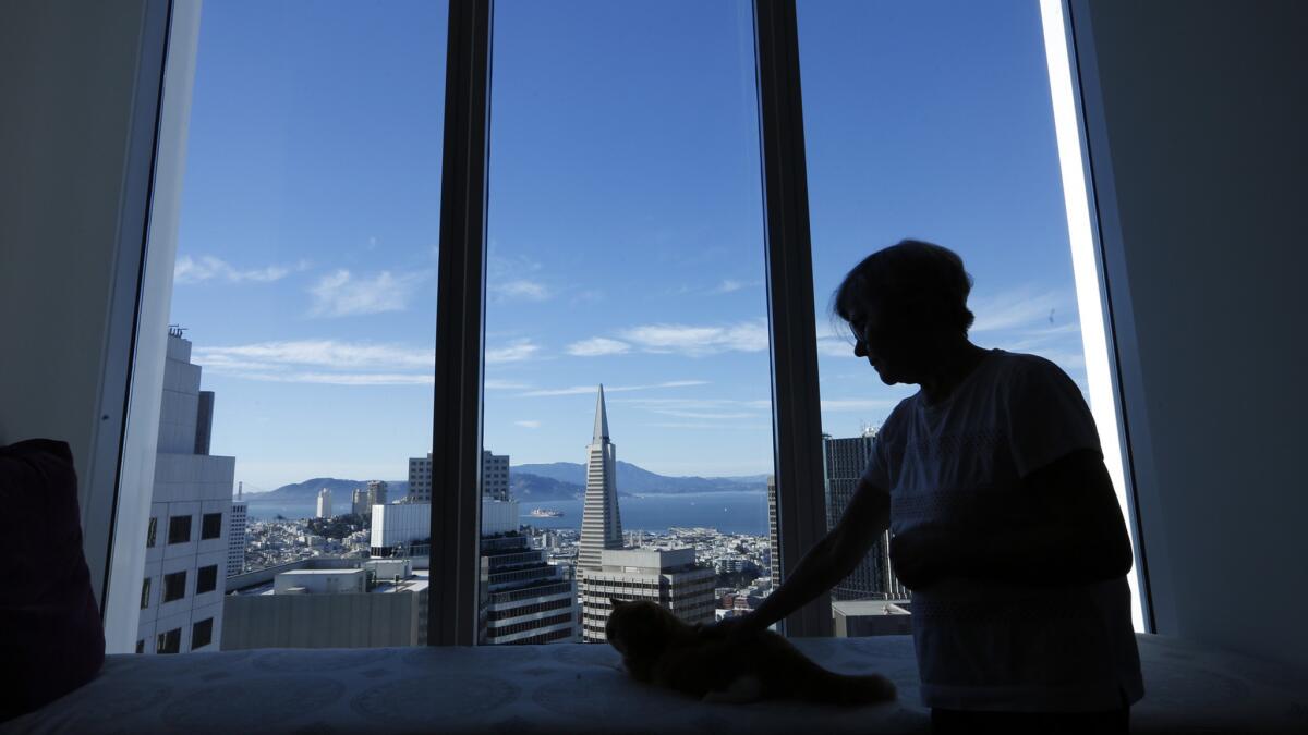 Pamela Buttery pets her cat Maximus inside her apartment in the Millennium Tower.