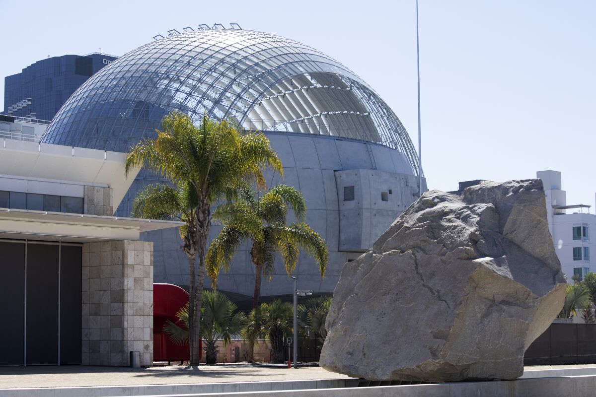 The Academy Museum's spherical building is seen behind LACMA's "Levitated Mass."