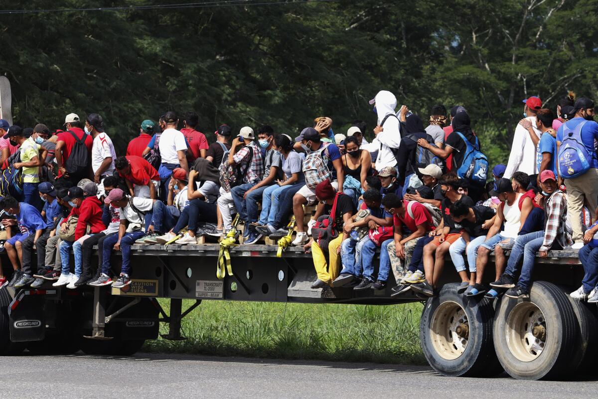 Un grupo de migrantes viaja en la plataforma de un camión por una carretera de Santa Rosa de Copán, Honduras