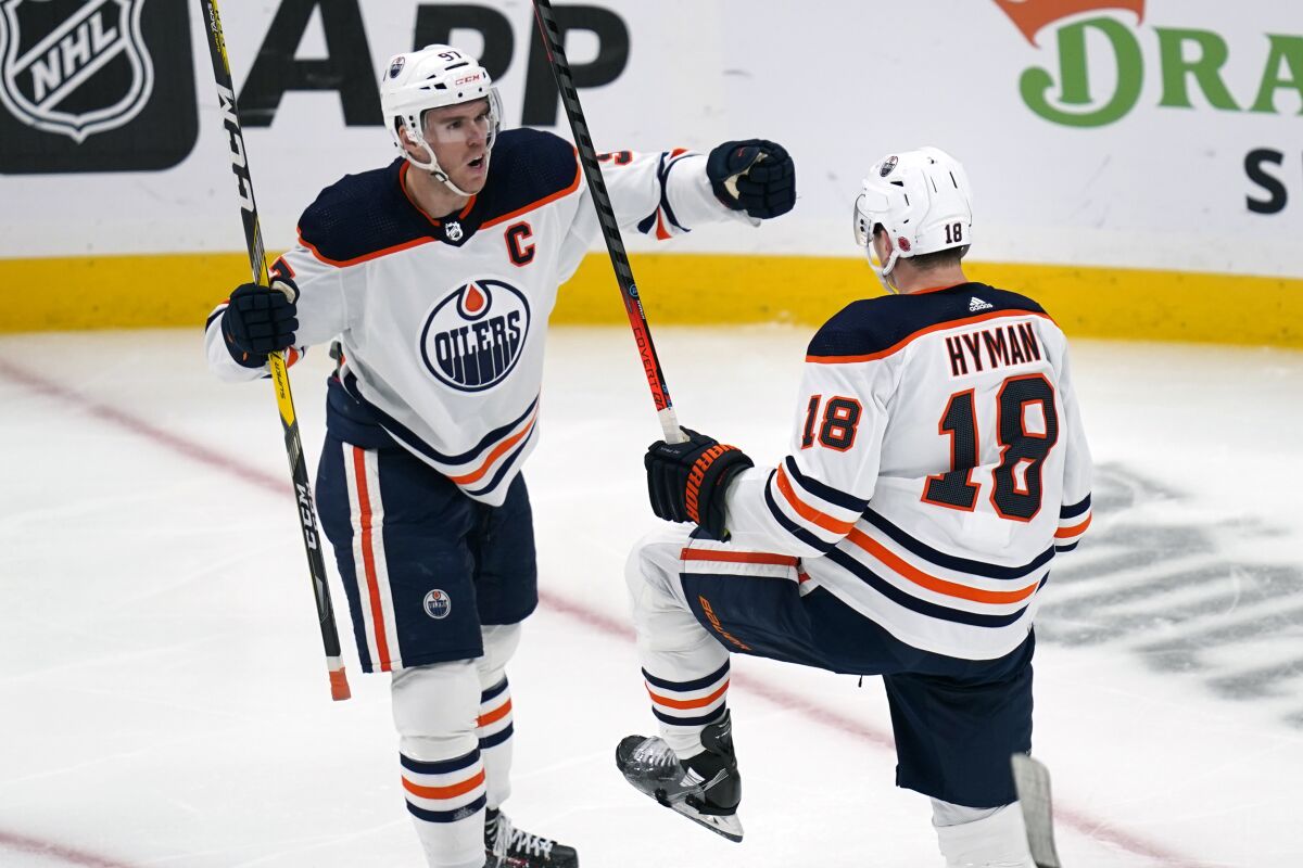 Edmonton Oilers left wing Zach Hyman (18) celebrates with Connor McDavid, left, after his goal during the second period of an NHL hockey game against the Boston Bruins, Thursday, Nov. 11, 2021, in Boston. (AP Photo/Charles Krupa)