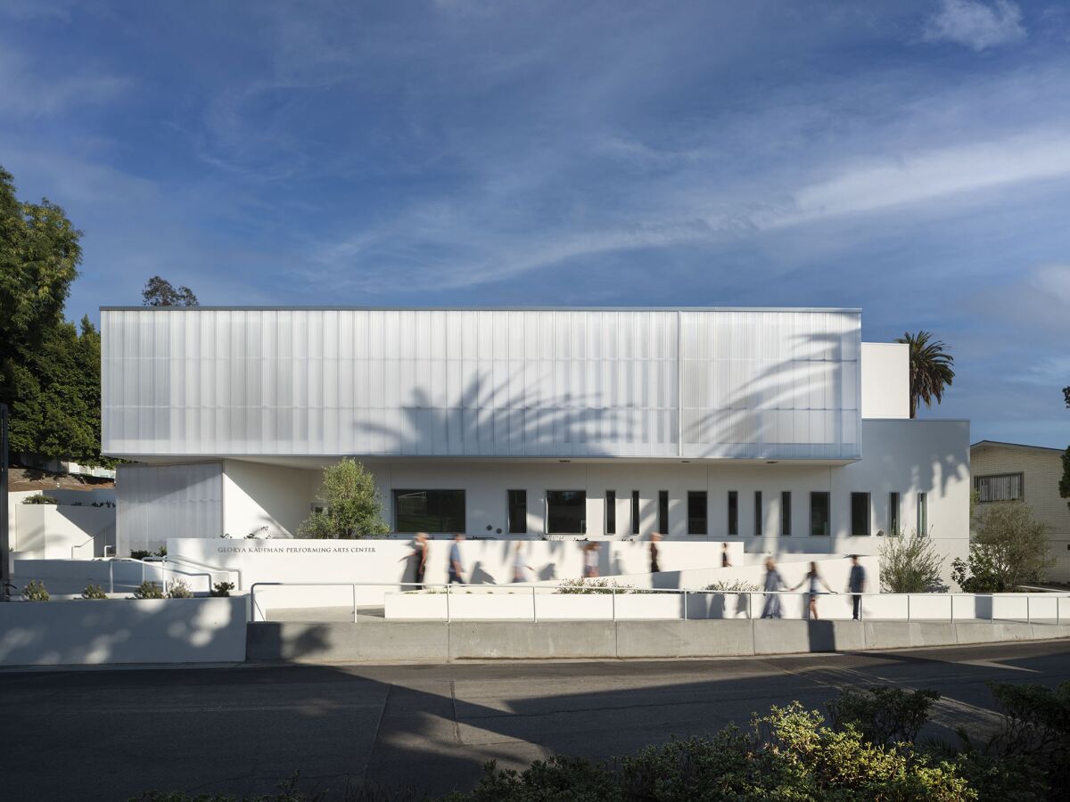 A building facade shows two white horizontal volumes stacked one on the other, with windows set in an irregular pattern