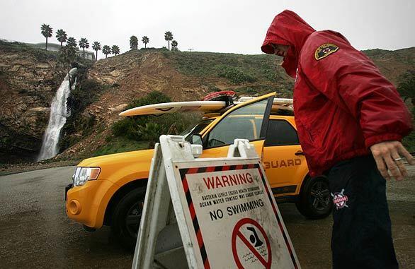 Los Angeles County lifeguard Will Douglas places a "no swimming" sign at Royal Palms State Beach in San Pedro.