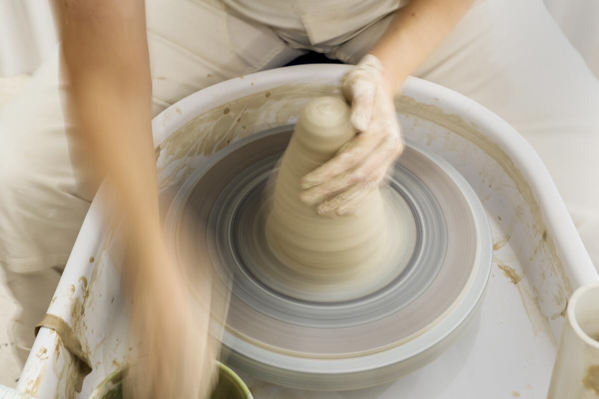 Potter Becki Chernoff molds clay while working on a wheel. 