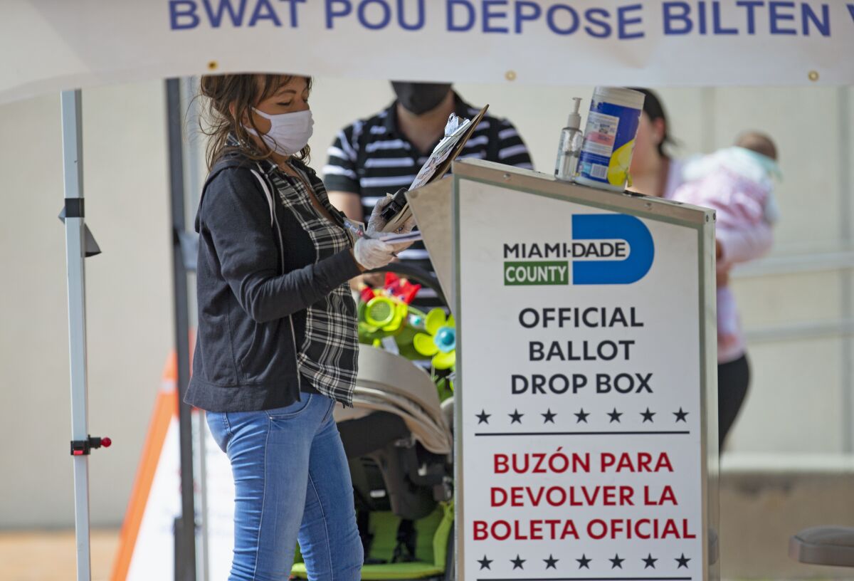 Poll worker next to ballot drop box in Miami