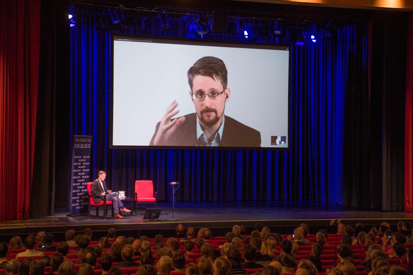 Edward Snowden is projected on a screen as he speaks during a video conference in Berlin to present his book, "Permanent Record," on Sept. 17.