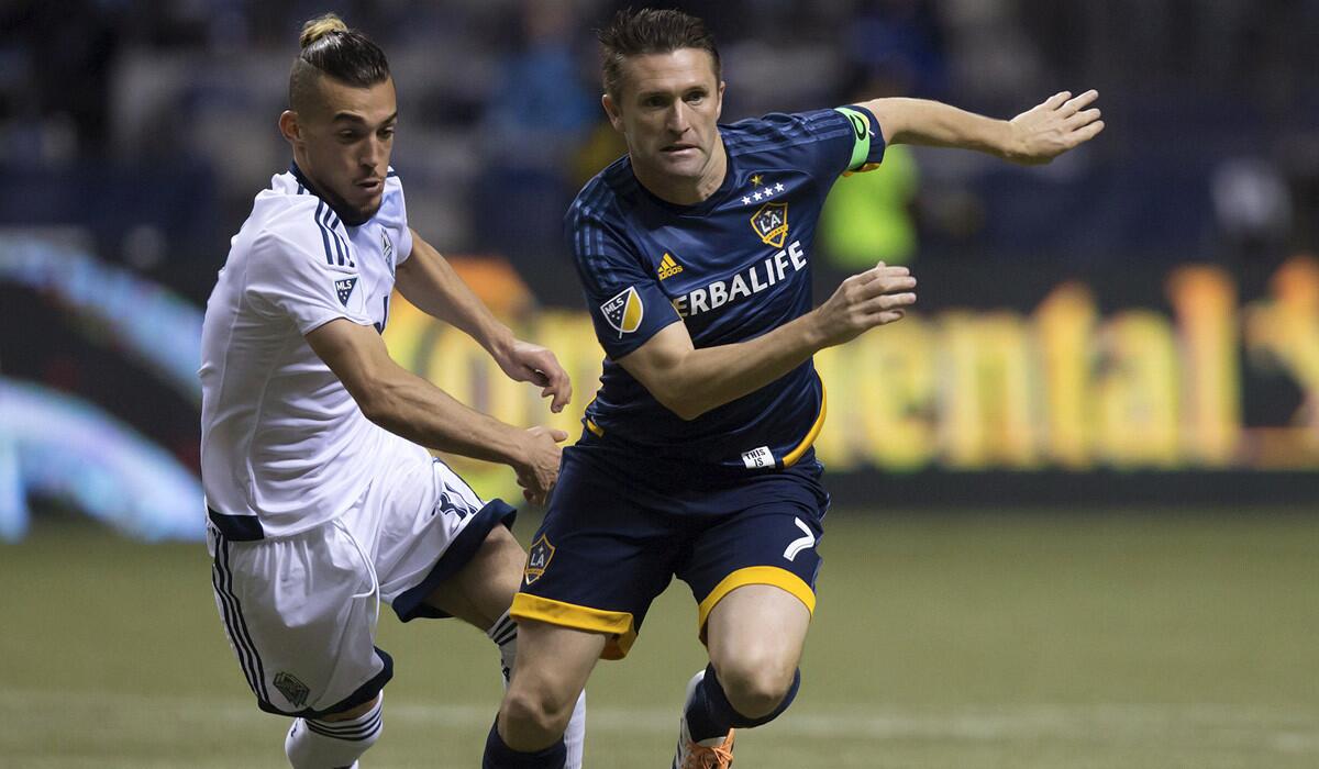 Los Angeles Galaxy's Robbie Keane tries to get away from Vancouver Whitecaps' Russell Teibert during the Galaxy's 2-0 loss to the Whitecaps.