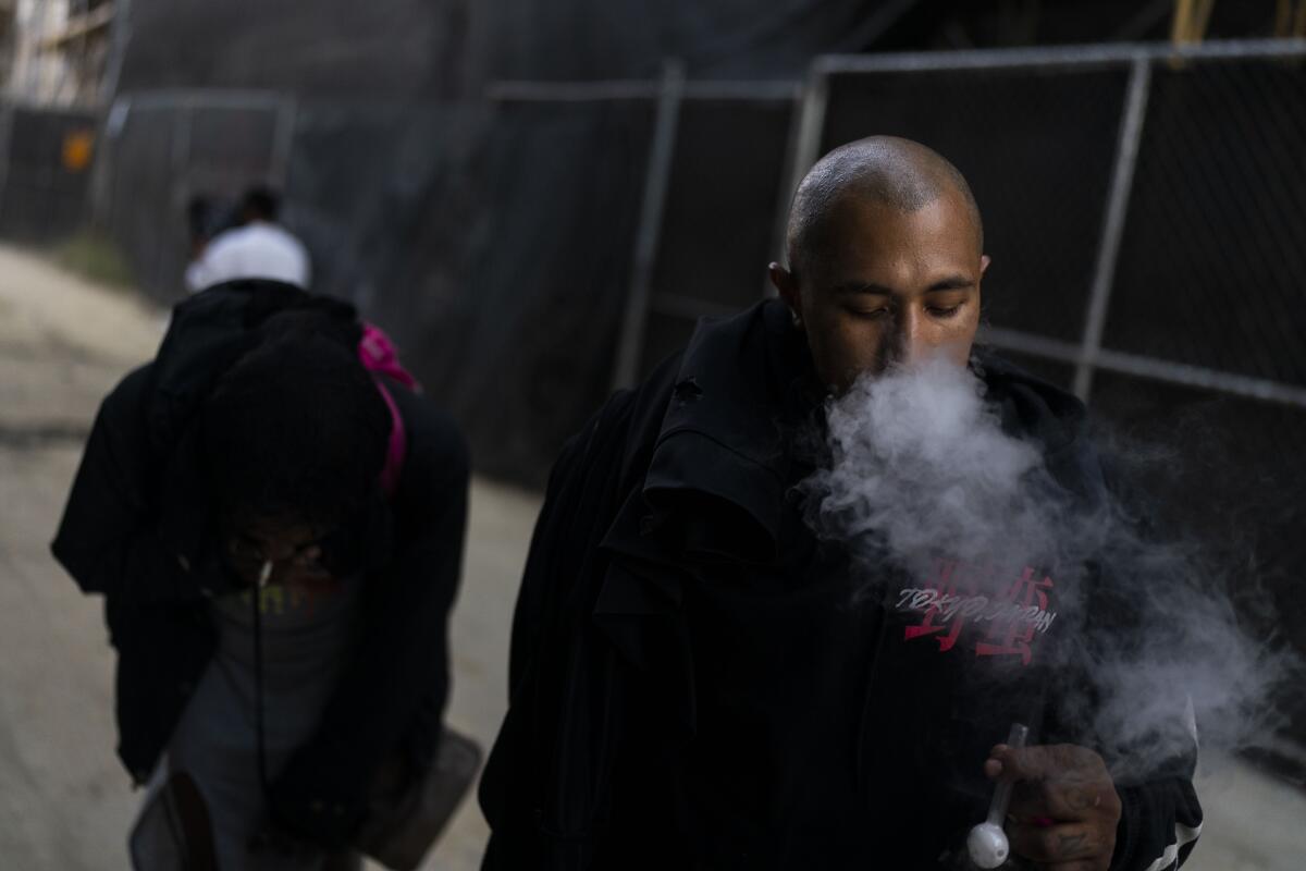 A man smokes exhales a cloud of smoke.