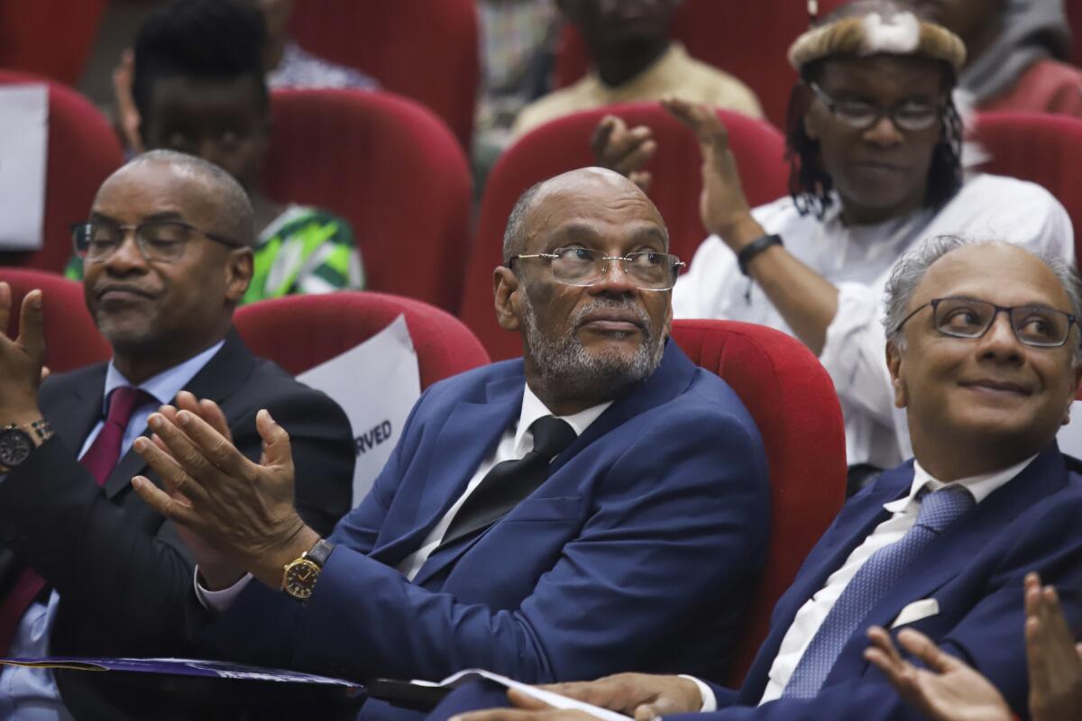 Haiti's Prime Minister Ariel Henry applauds while sitting in an audience.
