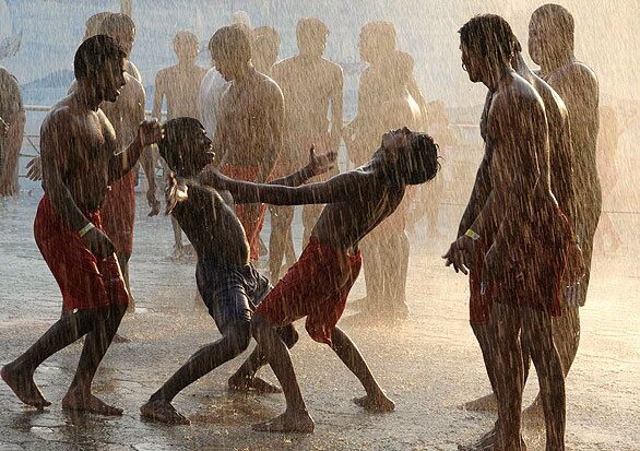 Indian youths dance and cool off in artificial rain at a water park.
