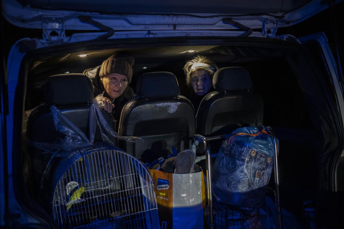 Evacuees in a vehicle with luggage and a bird in a cage.