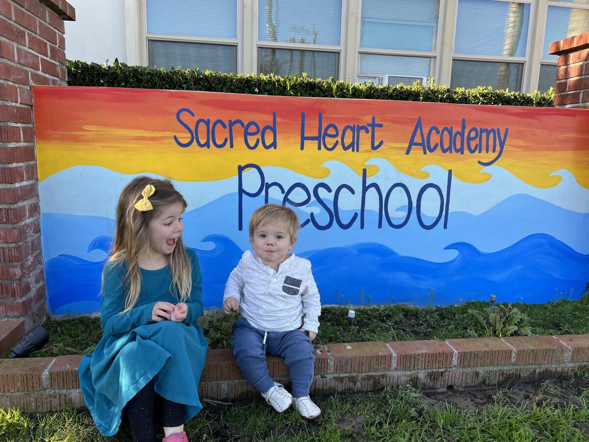 Rosie and William Lehman with the sign at Sacred Heart Academy in Ocean Beach that was painted by their mother, Diane.