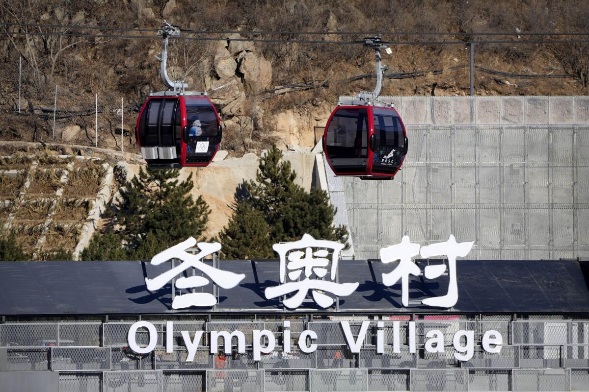 Gondolas glide past the Olympic Village in Beijing.