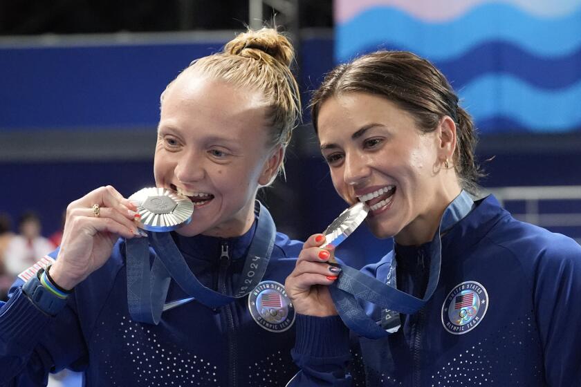 United States' Sarah Bacon and Kassidy Cook bite their silver medal.