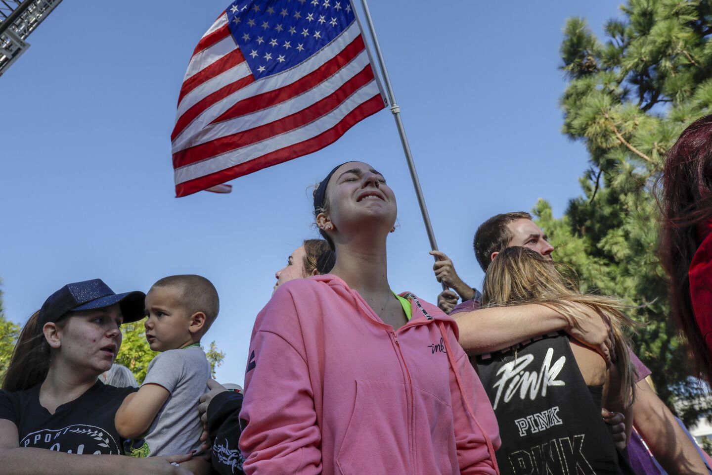 From left, Alexis Tait, 23, Rachel Berg, 20, and Harrison King, 24, weep as the hearse carrying Ventura County Sheriff's Sgt. Ron Helus leaves Los Robles Regional Medical Center for the medical examiner's office in Ventura. The three were inside the bar when the shooting took place.