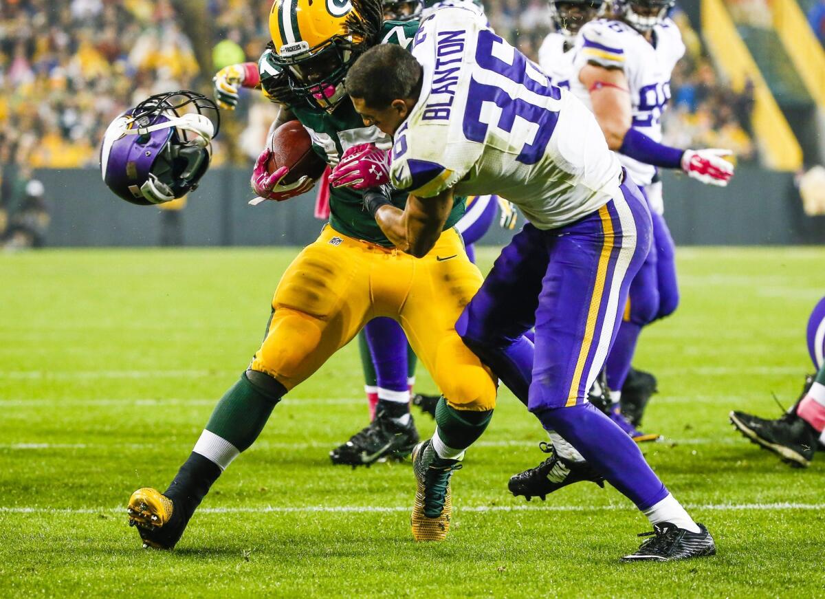 Green Bay Packers player Eddie Lacy, left, knocks the helmet off of Minnesota Vikings defensive player Robert Blanton as he runs for a touchdown.