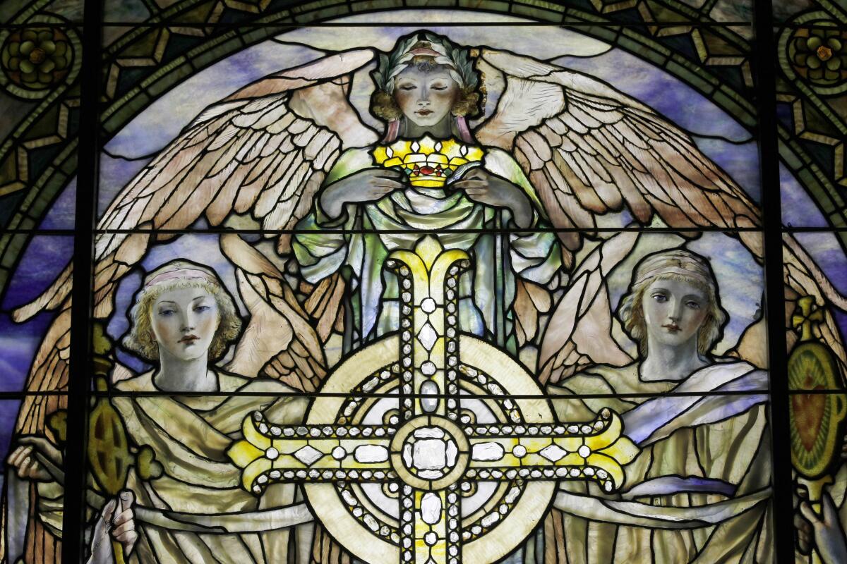 A detail of a stained glass window depicting angels around a cross. 