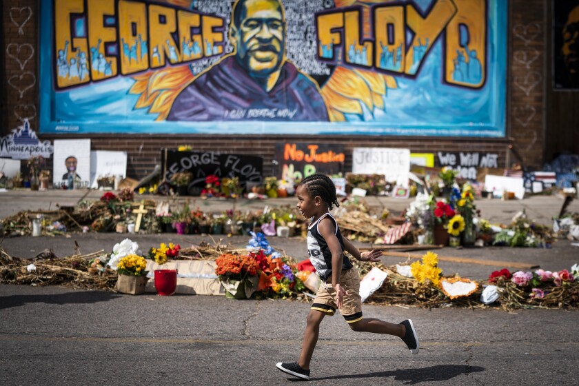 A 3-year-old boy runs past a mural at a George Floyd memorial in Minneapolis in June.