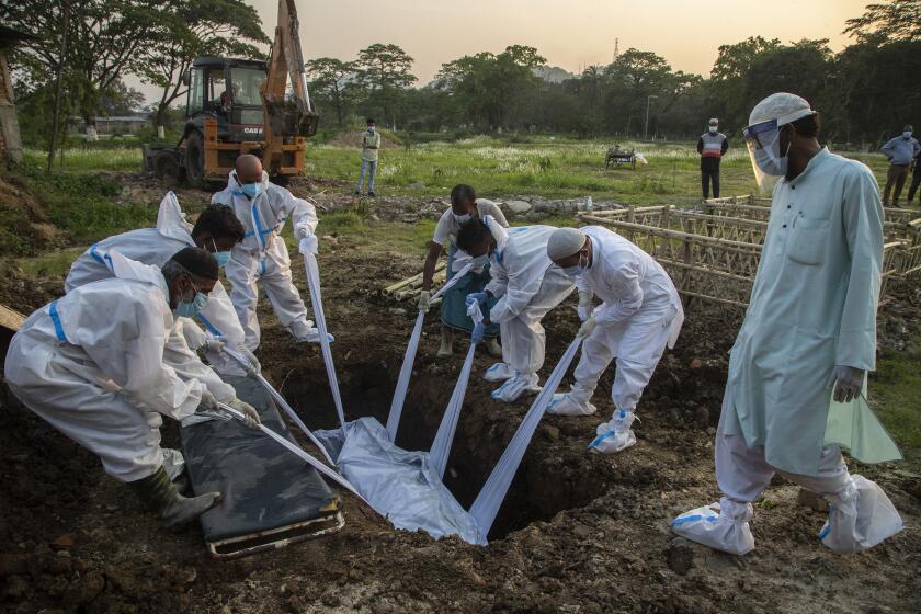 Relatives and municipal workers in protective suit bury the body of a person who died due to COVID-19 in Gauhati, India, Sunday, April 25, 2021. Delhi has been cremating so many bodies of coronavirus victims that authorities are getting requests to start cutting down trees in city parks, as a second record surge has brought India's tattered healthcare system to its knees. (AP Photo/Anupam Nath)