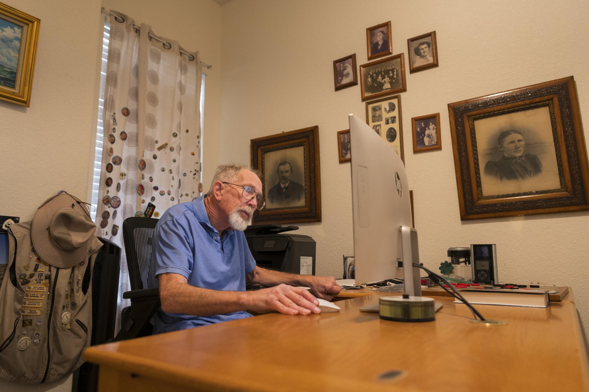 Surrounded by family photos, Gary Mund checks his email in Sparks, Nev.