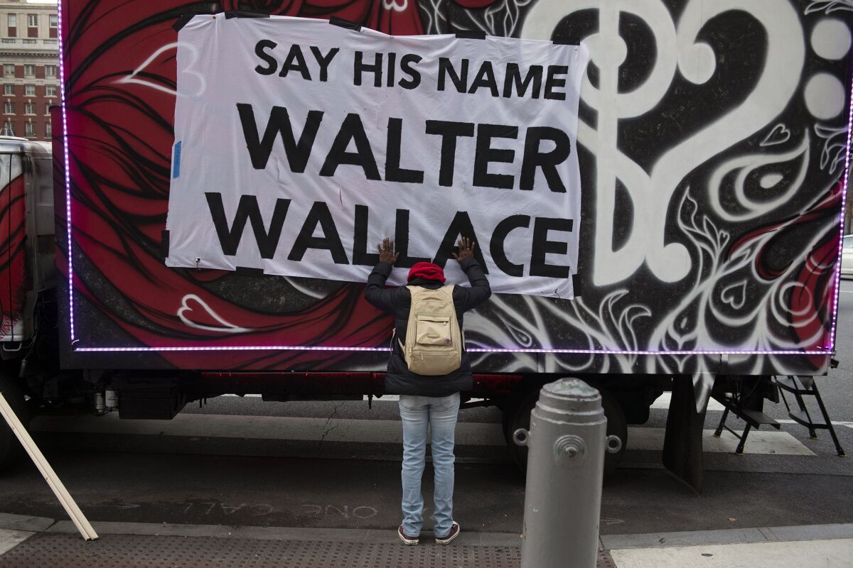Sheila Rhames rests her hands on a banner honoring Walter Wallace Jr. in Philadelphia, Wednesday, Nov. 4, 2020. Wallace, a Black man, was shot and killed by police in West Philadelphia, last month. Rhames was his neighbor. (Joe Lamberti/Camden Courier-Post via AP)