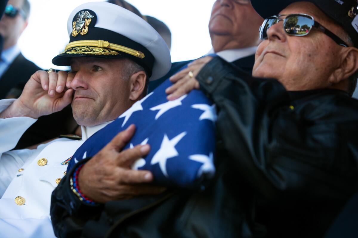 Rear Admiral Theodore LeClair, deputy commander, U.S. 7th Fleet, left, wipes his face as Ruben Valencia, right, holds onto a folded flag during a burial service for Raul Guerra at Rose Hill Memorial Park. (Dania Maxwell / Los Angeles Times)