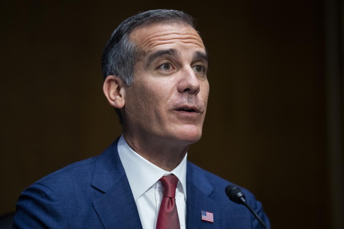 A portrait of a man with salt-and-pepper hair, in a blue suit and red tie 