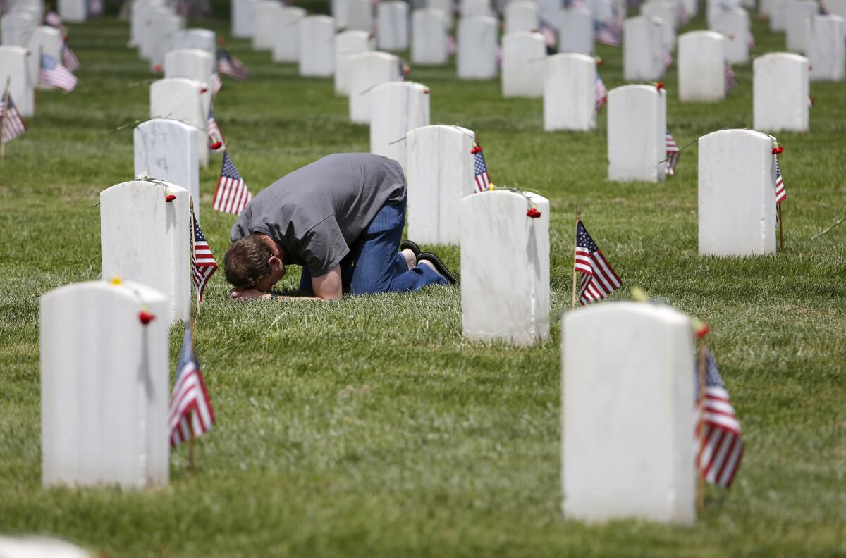 Chris Rake of Newbury Park prays near a gravestone in the Los Angeles National Cemetery. Rake says he did not know the soldier whom he prayed over, but that he feels he owes a debt of gratitude to those killed.